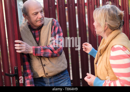 Woman is quarreling and having conflict with her neighbour at fence door Stock Photo