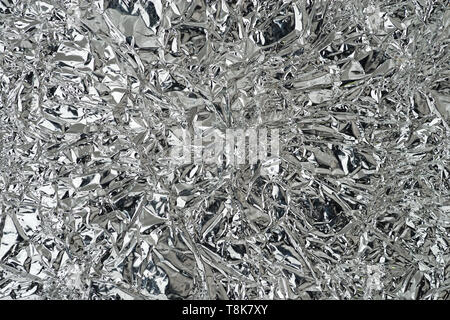 wrinkled and bent silver reflective metal foil background texture Stock Photo