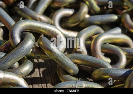 chain links piled up on old wood board Stock Photo