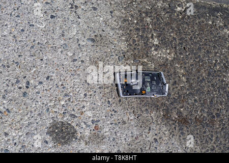 broken and smashed run over smartphone on a stained asphalt road Stock Photo