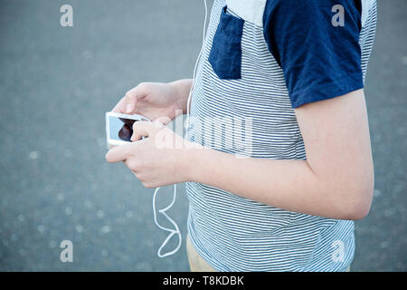 Boy walking on road while using smart phone Stock Photo