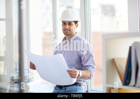 Smiling Middle-Eastern Engineer Holding Plans Stock Photo