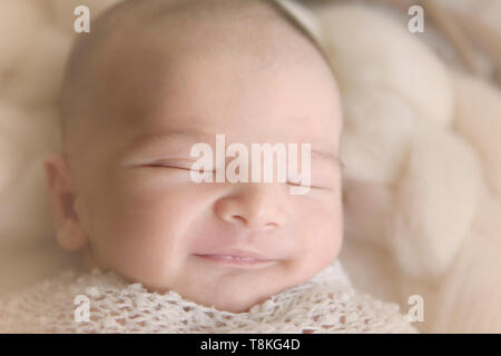 Newborn baby boy smiling as he is sleeping Stock Photo