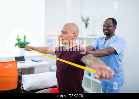 Sportsman holding ribbon stretching arms visiting therapist Stock Photo