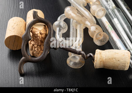 Fermentation tube and corkscrew on a black table. Accessories needed to prepare homemade wine. Dark background. Stock Photo