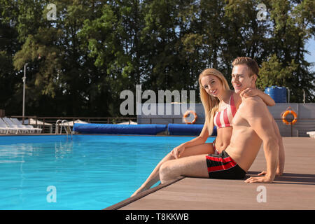Happy young couple resting near swimming pool at resort Stock Photo