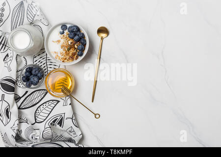 Free space for text with granola, blueberries, honey and yogurt, spoon and napkin. Ingredients for healthy breakfast, concept of diet food, flat lay,  Stock Photo