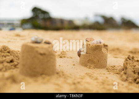 Selective focus colour photograph of two sand castle turrets on beach with only one in focus on cloudy day. Stock Photo