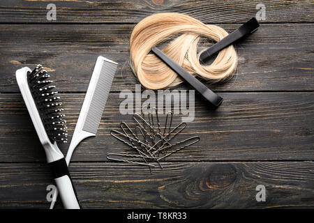 Professional hairdresser's set with strand of blonde hair on wooden background Stock Photo