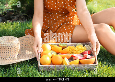 Young woman with various delicious fruits on summer picnic in park Stock Photo