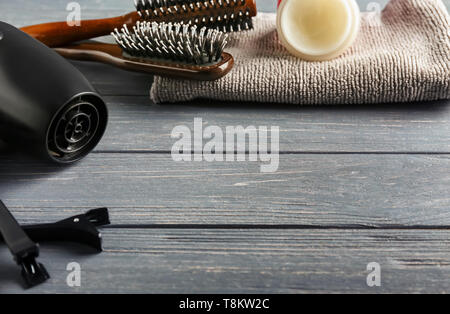 Dryer with brushes, clips, cosmetics and towel on wooden table Stock Photo