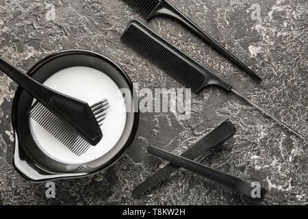 Bowl with hair dye, combs and clips on grey background Stock Photo