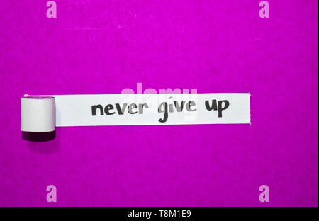 Never give up text, Inspiration, Motivation and business concept on purple torn paper Stock Photo