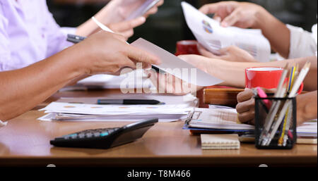 Asian businesswomen analysis documents on office table with laptop computer and graph financial diagram working in the background Stock Photo