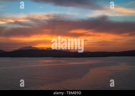 Sunrise on the Sardinian sea coast with intense orange color seen from the sea Stock Photo
