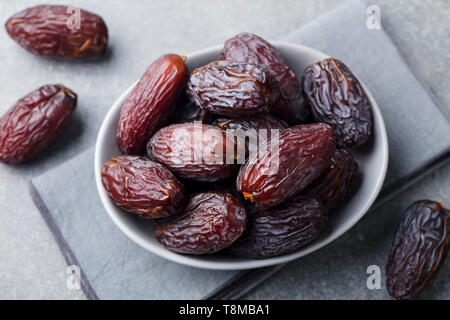 Fresh medjool dates in bowl. Grey background. Close up. Stock Photo