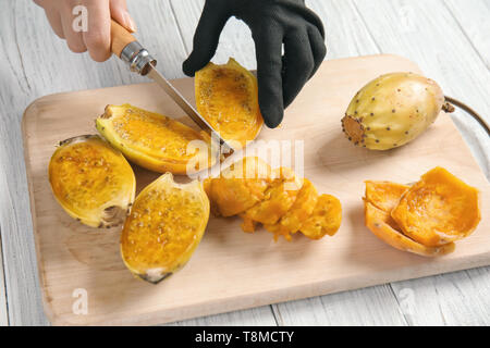 Woman cutting ripe cactus pear on wooden board Stock Photo