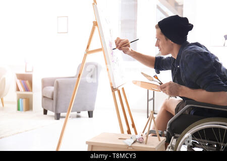 Young artist in wheelchair painting picture at home Stock Photo