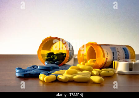 Two prescription bottles overturned with blue and yellow pills spilling out on the table with a white background, representing America's epidemic of p Stock Photo