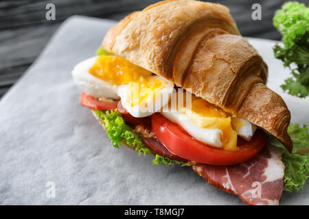 Tasty croissant sandwich with meat and egg on table Stock Photo