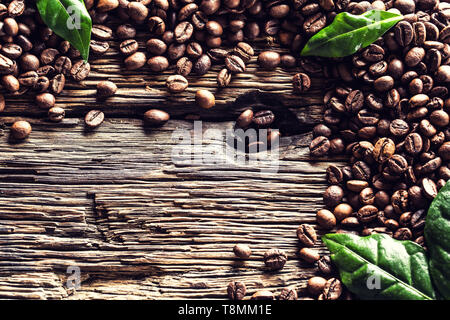 Top of view coffee beans and green leaves on rustic oak table Stock Photo