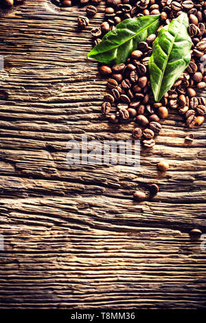 Top of view coffee beans and green leaves on rustic oak table Stock Photo
