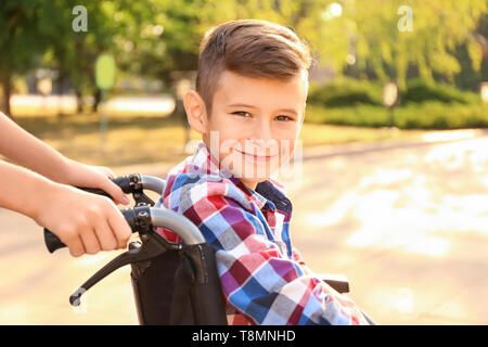 Boy in wheelchair and his sister outdoors Stock Photo