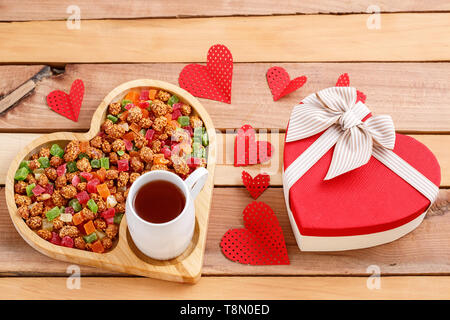 colorful dried fruits,tea and a heart-shaped gift on a wooden background Stock Photo