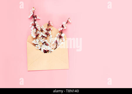 Spring concept. Opened envelope with flowers arrangements on pink background, top view. Stock Photo