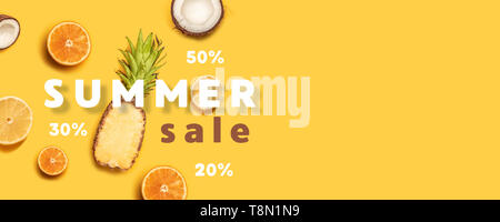 Creative summer composition of tropical fruit juices on a yellow background: oranges, coconuts, lemons, pineapples. Stock Photo