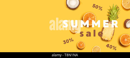 Juicy tropical fruits on a yellow background: oranges, coconuts, lemons, pineapples. Stock Photo