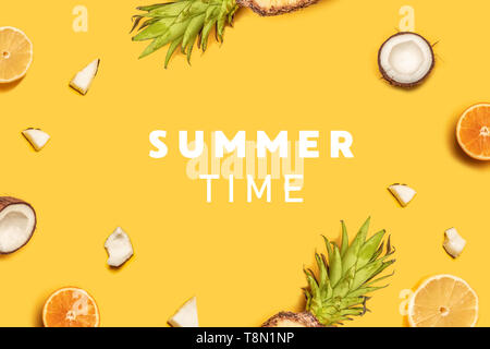 Pineapples, oranges, lemons, coconuts on yellow background. Summer fruits. Flat lay, top view, copy space Stock Photo