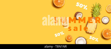 Juicy tropical fruits on a yellow background: oranges, coconuts, lemons, pineapples. Stock Photo