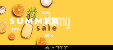 Pineapples, oranges, lemons, coconuts on yellow background. Summer fruits. Flat lay, top view, copy space Stock Photo