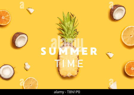 Creative summer composition of tropical fruit juices on a yellow background: oranges, coconuts, lemons, pineapples. Stock Photo