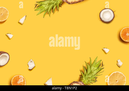 Creative summer composition of tropical fruit juices on a yellow background: oranges, coconuts, lemons, pineapples. Stock Photo
