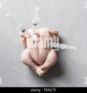 Fresh chicken with stuck syringes on concrete background. View from above. Stock Photo