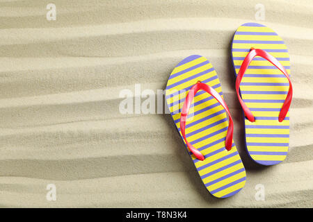 Clear sea sand with flip flops, space for text and top view. Summer vacation background Stock Photo