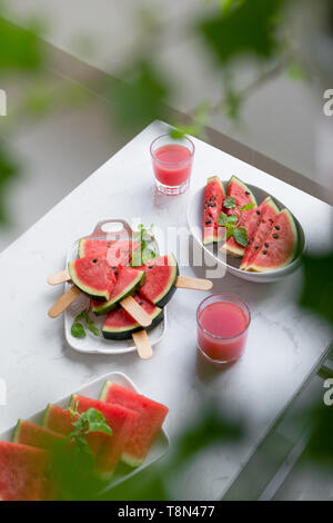 Fresh red smoothie in a glass with sliced pieces of watermelon on table. Stock Photo