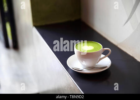 White cup of tasty matcha latte with love art. Valentine's concept. Black stone backdrop. Stock Photo