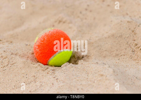 tennis ball on the sand at the beach close up Stock Photo