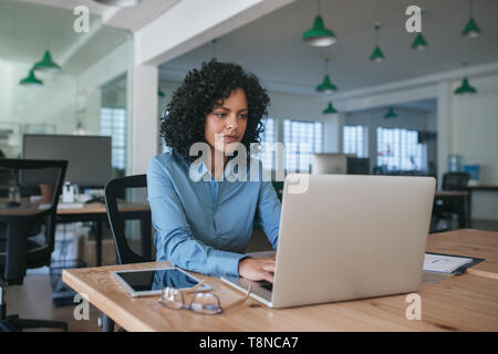 Focused young businesswoman using a laptop at her office desk Stock Photo