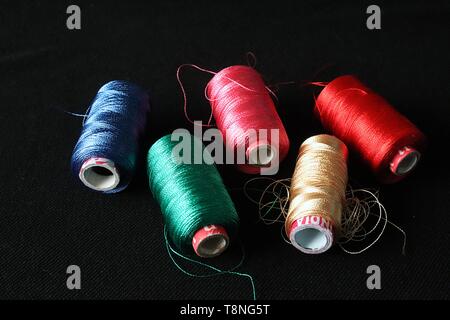 Blue, Green , Orange, Cream and Red Silk thread rolls on black background. Stock Photo