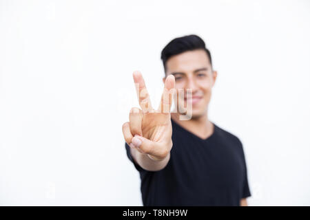 Handsome latin hispanic man is showing two fingers isolated on white background. Place for text and design. Stock Photo