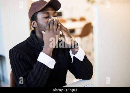 Sick young african-american businessman wearing suit caught cold sneezing in tissue working in office, black frustrated employee got flu influenza cou Stock Photo