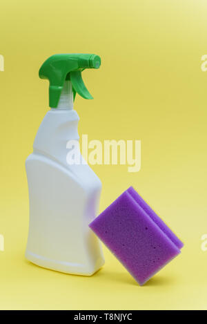 Chemical cleaner in spray and purple sponge on yellow background. Home or hotel cleaning concept Stock Photo