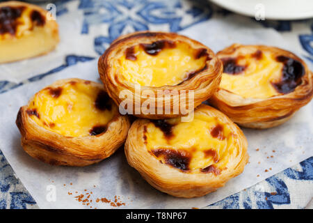 Egg tart, traditional Portuguese dessert, pastel de nata on a plate. Blue textile background. Stock Photo