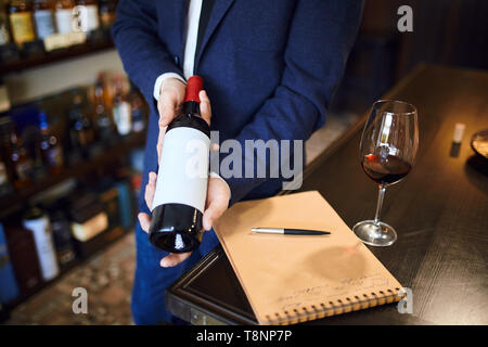 professional talented sommilier choosing bottle of wine. close up cropped photo.would you like a bottle of wine . trade concept Stock Photo