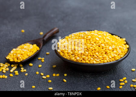 Yellow lentil in black bowl and scoop on slate background. Copy space. Stock Photo