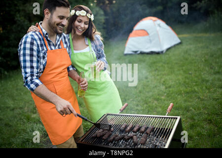 Happy group of friends making a barbecue together outdoors in the nature Stock Photo